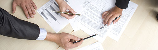 photograph of a table with forms and the hands of those completing them