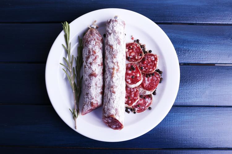 French salami on plate on dark blue wooden background.