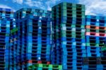 TOWERING PILES OF COLORED PLASTIC PALLETS SIT ON A DOCK