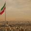 Iran flag waving in the wind above the skyline of Tehran lit by the orange glow of sunset.