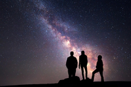 Three people gaze at the night sky.