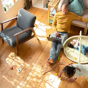 Father sitting on a hardwood floor working from home