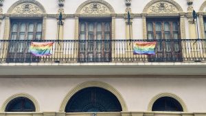 Two pride flags on the railing of a balcony.