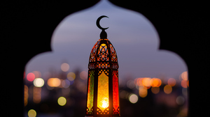 Lantern with a Moon symbol at the top and blurred city lights in the background.