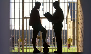 A CUSTODY OFFICER TALKS TO AN OFFENDER BEFORE A FOOTBALL