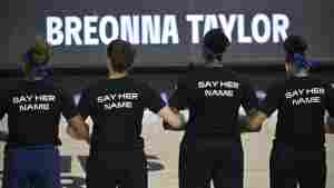 Minnesota Lynx players lock arms during a moment of silence in honor of Breonna Taylor before a game on in July 2020. Their black shirts say 