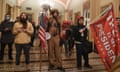 Insurrectionists with flags and red baseball hats, including QAnon conspiracist Jake Angeli, inside the US Capitol on 6 January 2021