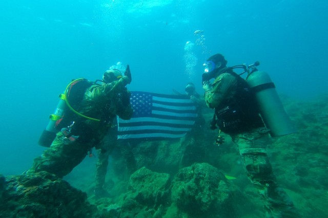 Amidst the serene backdrop of Okinawa&#39;s coastal waters, Maj. Robert S. Bourgeau and Sgt. 1st Class Corey O. Tomasich, accompanied by Capt. Erik McDowell and Capt. Timothy Robinson, prepare to descend for a significant underwater reenlistment....