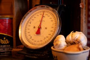 A classic kitchen scale with some garlic in the foreground.
