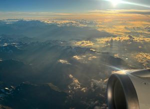 Italian Alps seen from above the clouds, airplane engine in the bottom right corner.