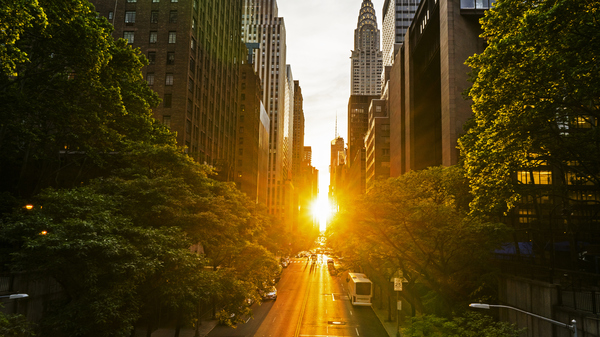 Setting Sun visible between skyscrapers lining 42nd street in New York.