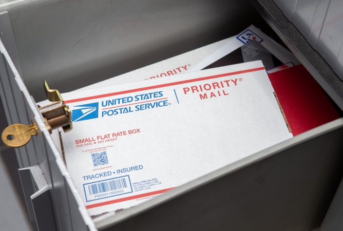 A PO Box with a key in the lock and mail in the box.