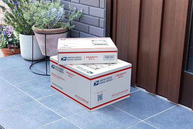 Priority Mail boxes on a house porch awaiting pickup.