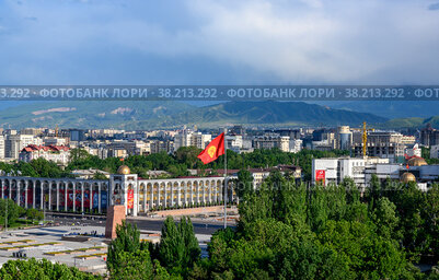 BISHKEK, KYRGYZSTAN - MAY 17, 2022: Panorama of Bishkek, the capital of Kyrgyzstan, with a central square, a monument to Manas, a national flag, against the background of mountains covered with clouds