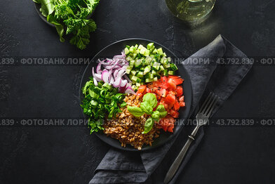 Cooked Whole Grain cereal spelt salad with seasonal vegetables in bowl on black background.