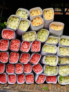 Different colours of roses are organised in paper boxes for sale. An early morning view from KR Market, Bengaluru, Karnataka.