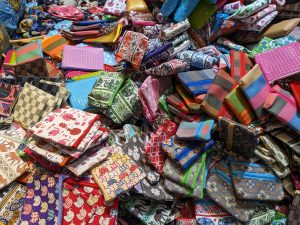 A lively jumble of colorful fabric pouches with all sorts of patterns—stripes, checks, and quirky cartoons—piled high like a treasure hunt in the heart of Bangkok's Chinatown.