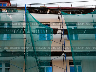 Scaffolding with protective mesh on building, facade restoration