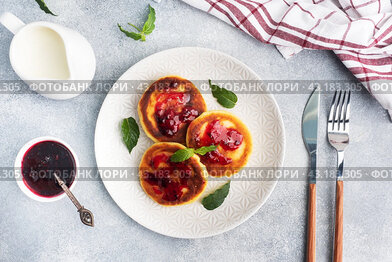 Fritters of cottage cheese with blueberries jam. Cheese curd cheesecakes, pancakes on a grey concrete background. Copy space.