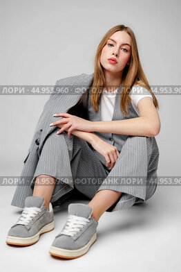 Young Woman in a Gray Suit Sitting on the Floor in Studio